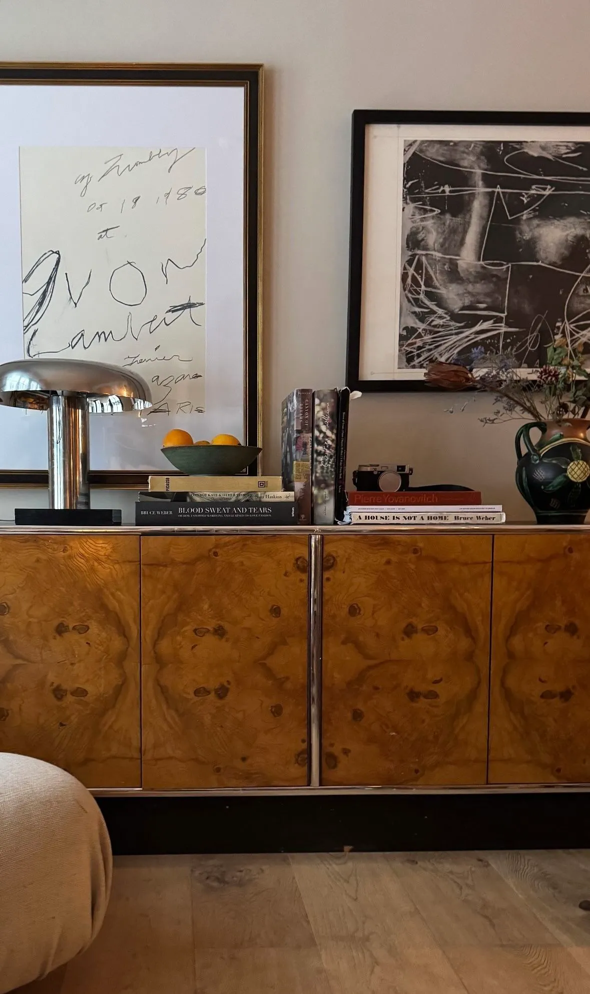 Burl wood sideboard with a mushroom lamp, framed artworks and a ceramic vase