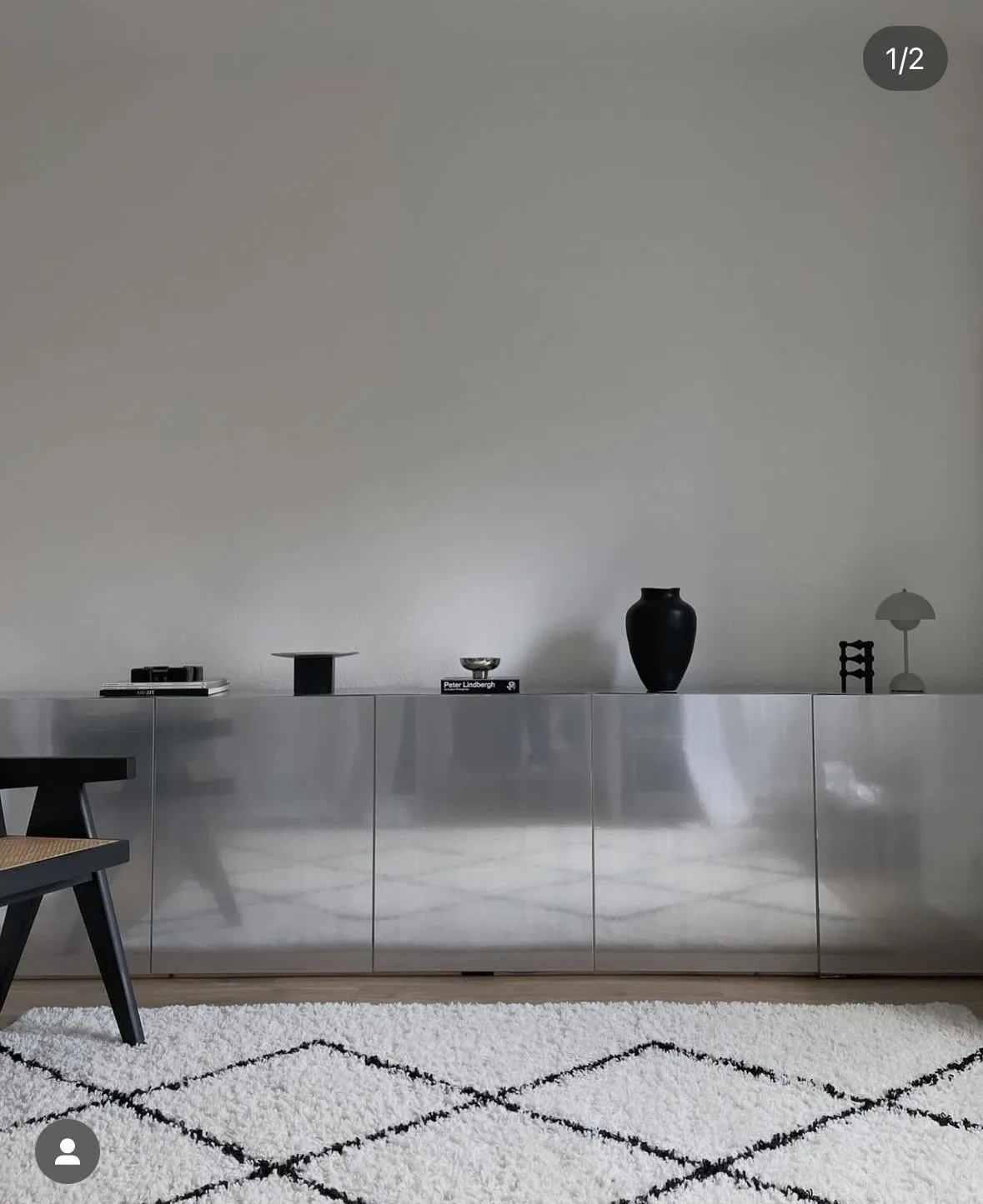 Mirrored steel sideboard with black vases above a Berber-style rug