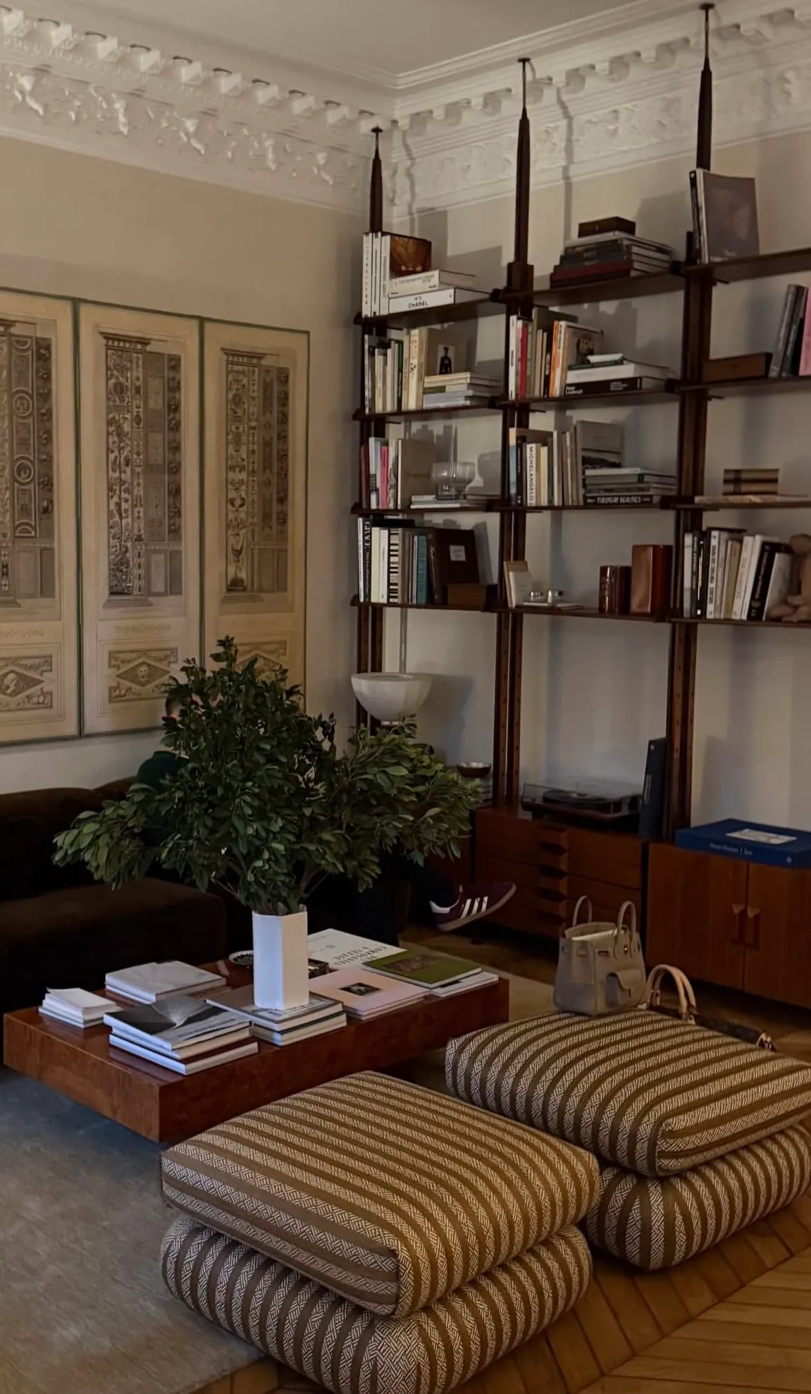Library wall of vintage shelving with books, striped floor cushions and framed textile panels