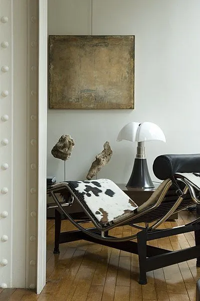 Le Corbusier LC4 chaise longue in cowhide beside a Pipistrello lamp and a vintage painting
