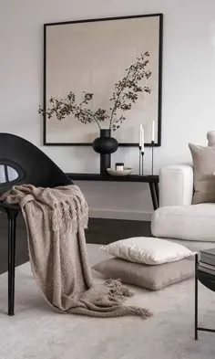 All-beige living room with a cream sofa, floor cushions, a knitted throw and a black vase