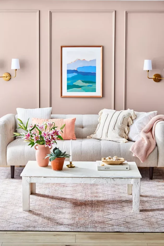 Blush-panelled living room with a tufted sofa, brass sconces and a white coffee table