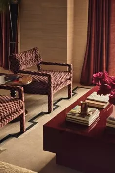 Woven upholstered armchairs, grasscloth walls and a glossy red lacquered coffee table