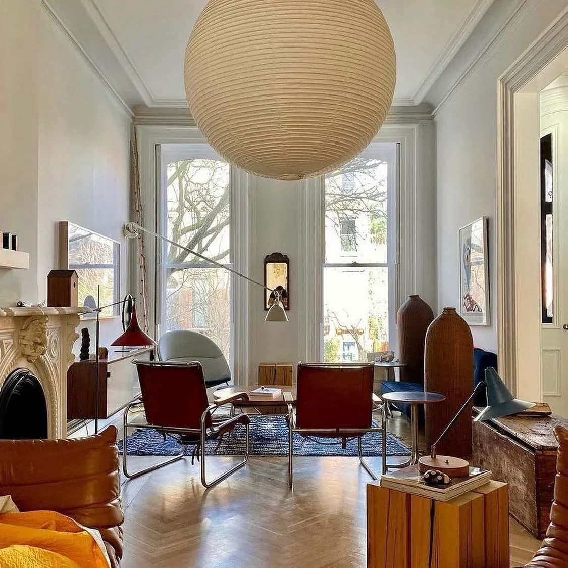 Bright living room with a large paper globe pendant, red sling chairs and a red task lamp