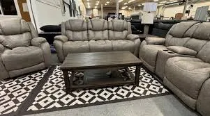Furniture showroom with matching grey reclining sofas and a dark coffee table