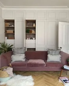 Panelled built-in cupboards with open niches behind a dusty pink velvet sofa