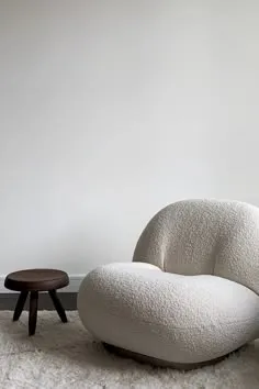 Cream bouclé lounge chair beside a dark wooden stool