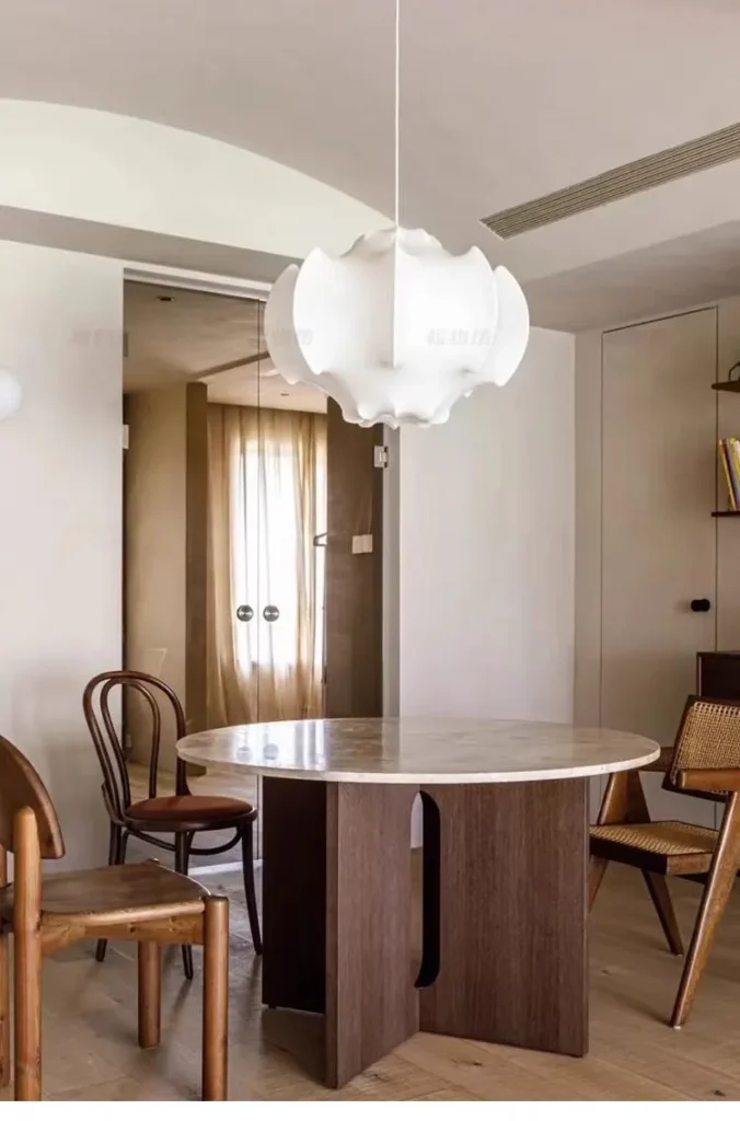 White Castiglioni cocoon pendant for Flos over a round marble dining table with bentwood chairs