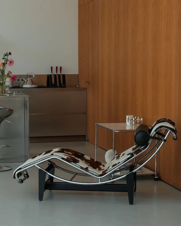 Le Corbusier LC4 chaise longue in cowhide against a warm wooden wall