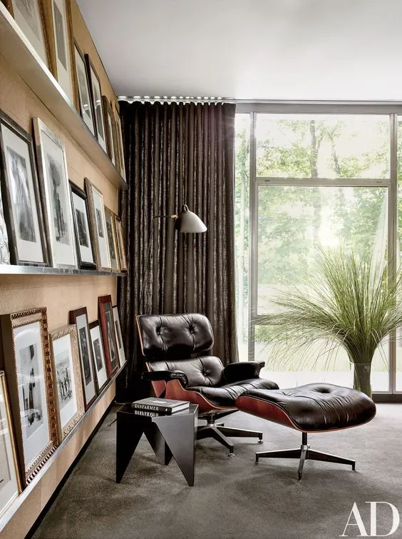Eames Lounge Chair and ottoman in a reading corner with a photo wall and floor-to-ceiling windows