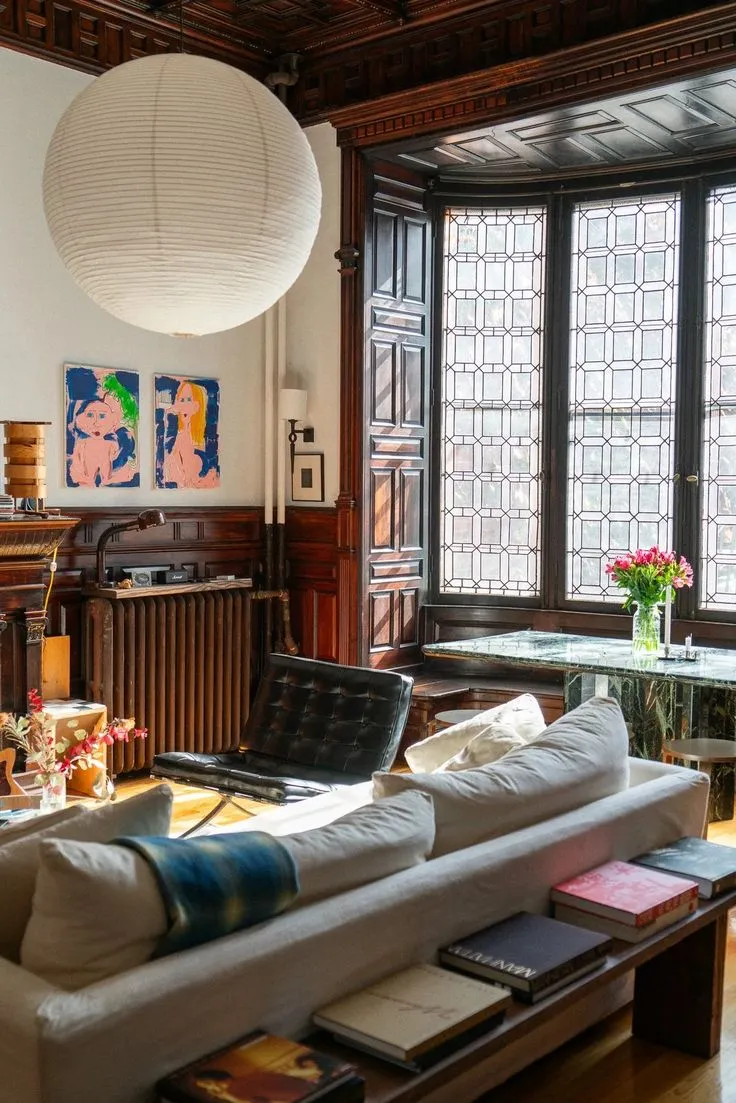 Black Barcelona Chair in a living room with a large paper globe pendant and leaded windows