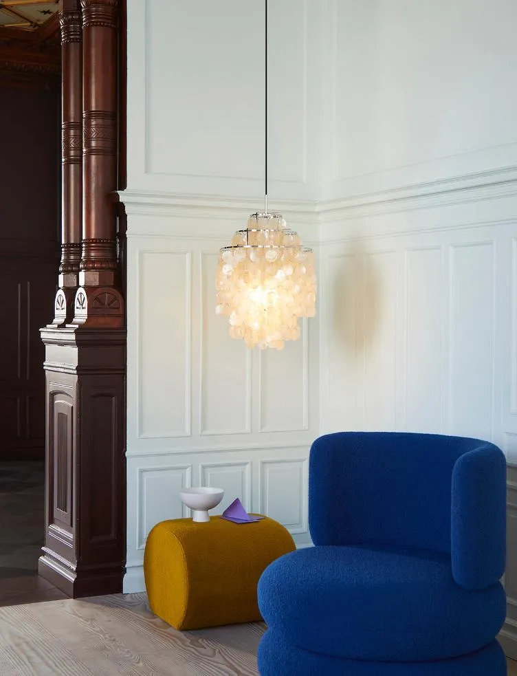 Verner Panton Fun 0DM shell pendant glowing in a panelled room with a blue armchair and mustard pouf