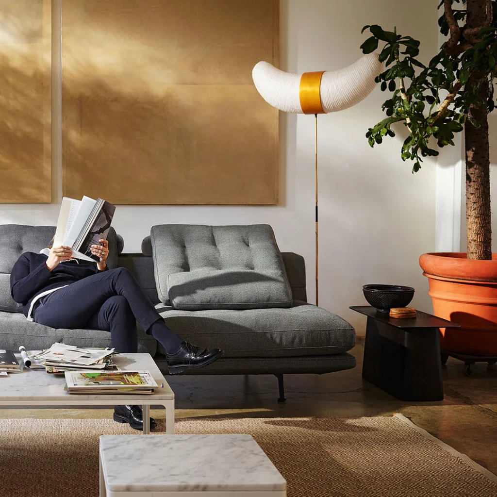 Isamu Noguchi Akari floor lamp beside a grey sofa in a sunlit living room