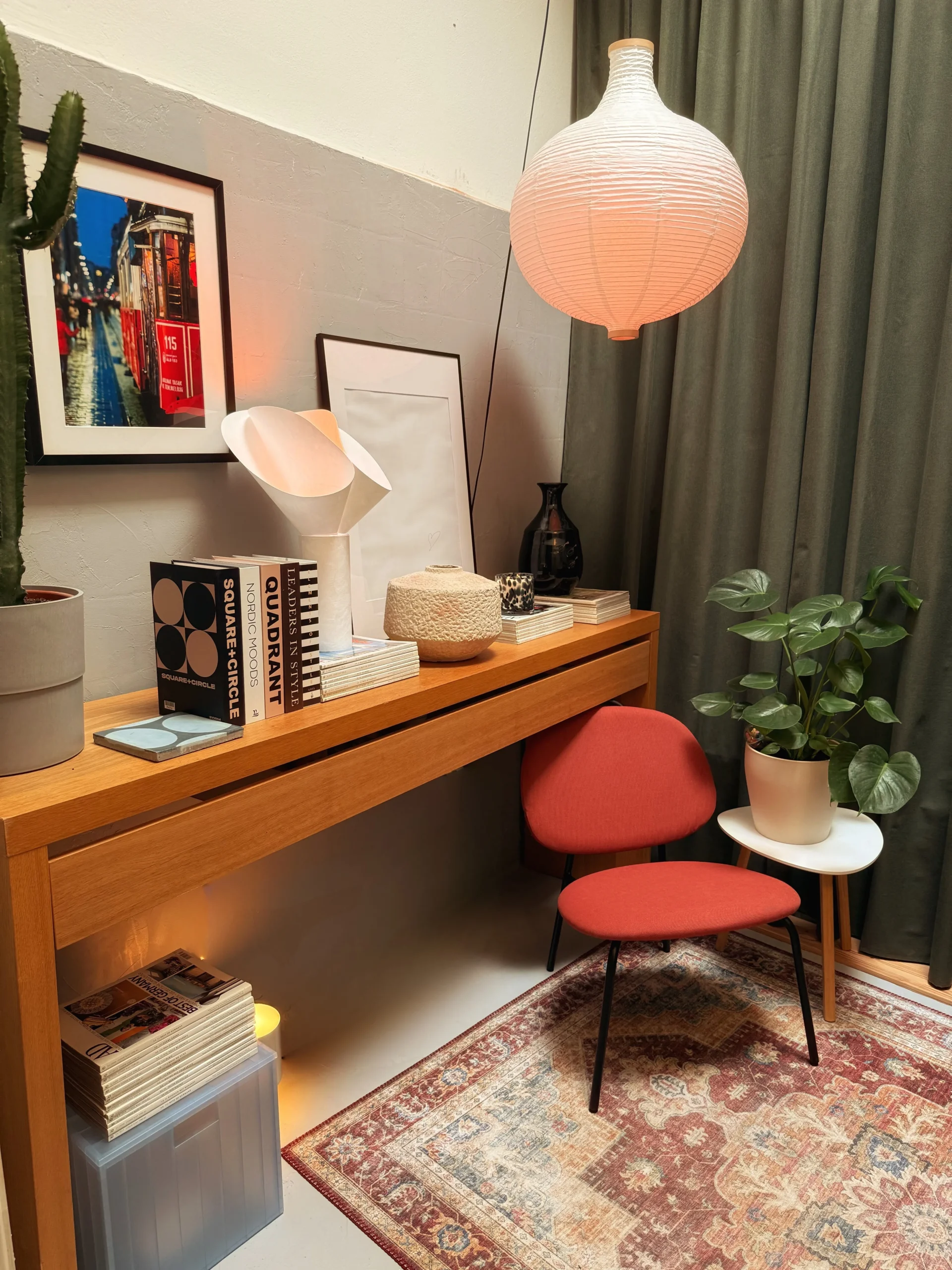 After: microcement office with a wooden console desk, red chair, paper pendant lamp and Persian rug by green curtains
