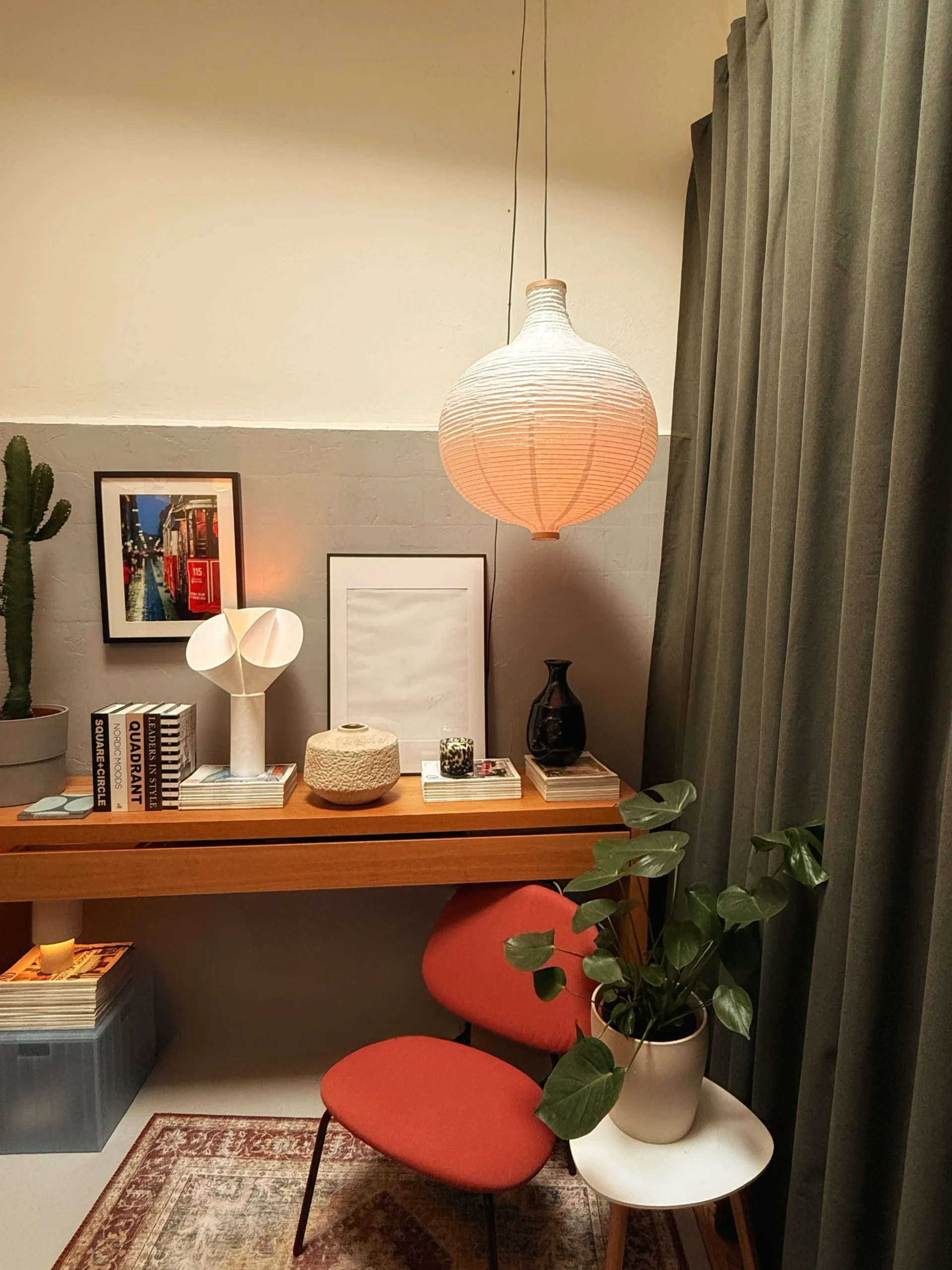 After: desk nook with a paper pendant lamp, red chair, cactus and framed prints against a two-tone wall