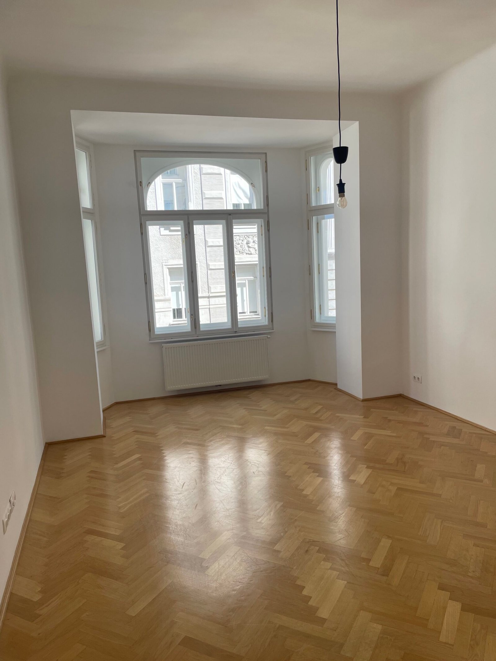 Before: empty room with a bay window and a bare bulb hanging from the ceiling