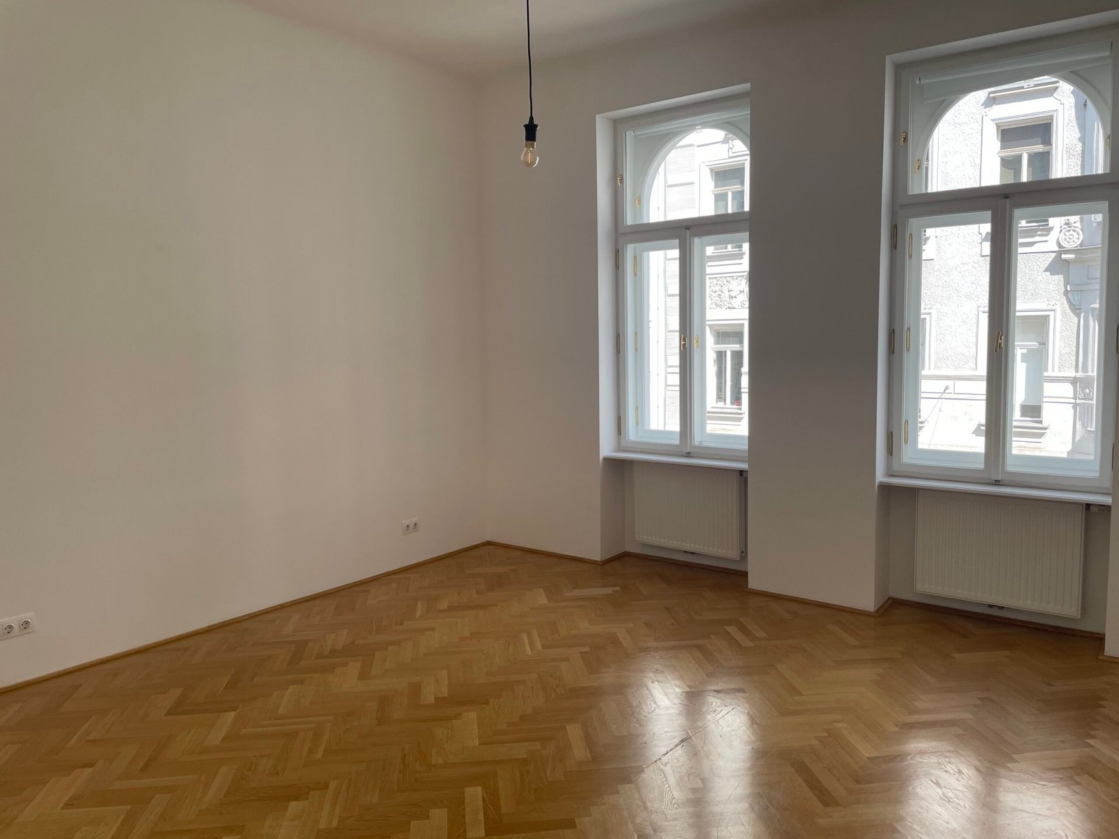 Before: empty room with two tall windows and herringbone parquet