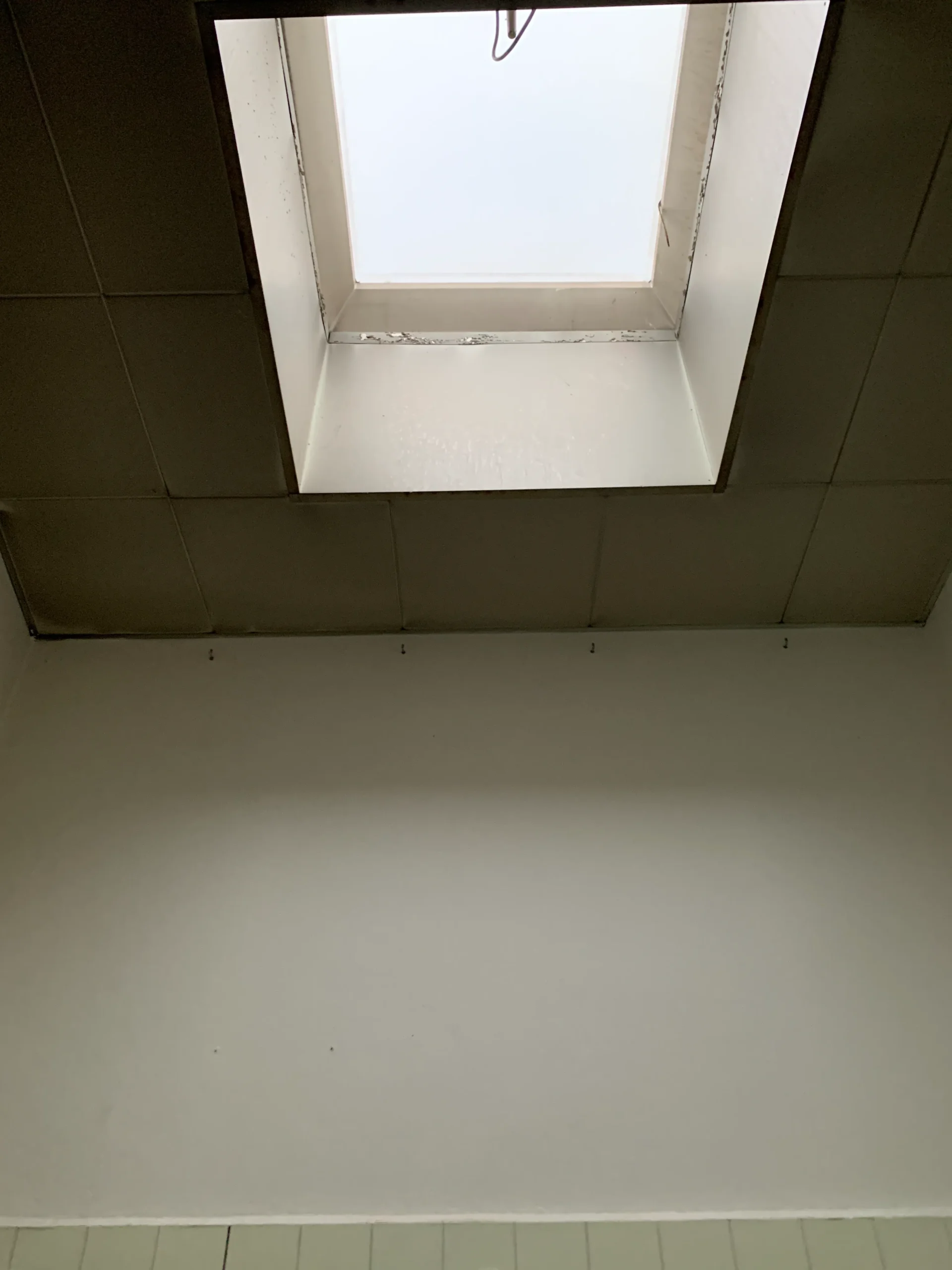 Before: skylight in the ceiling of the tiled shower room