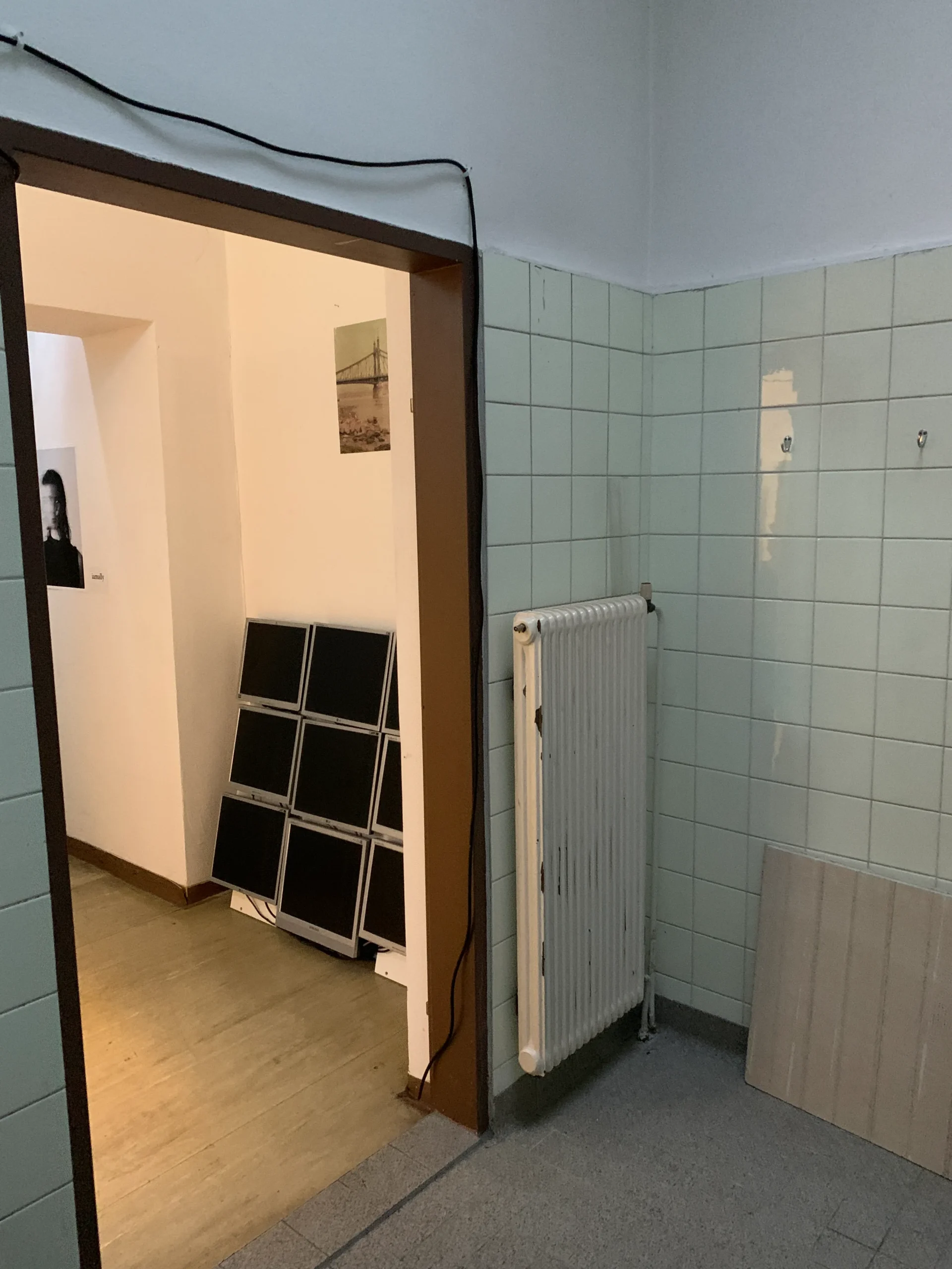 Before: doorway from the tiled shower room with a radiator, looking into the hallway