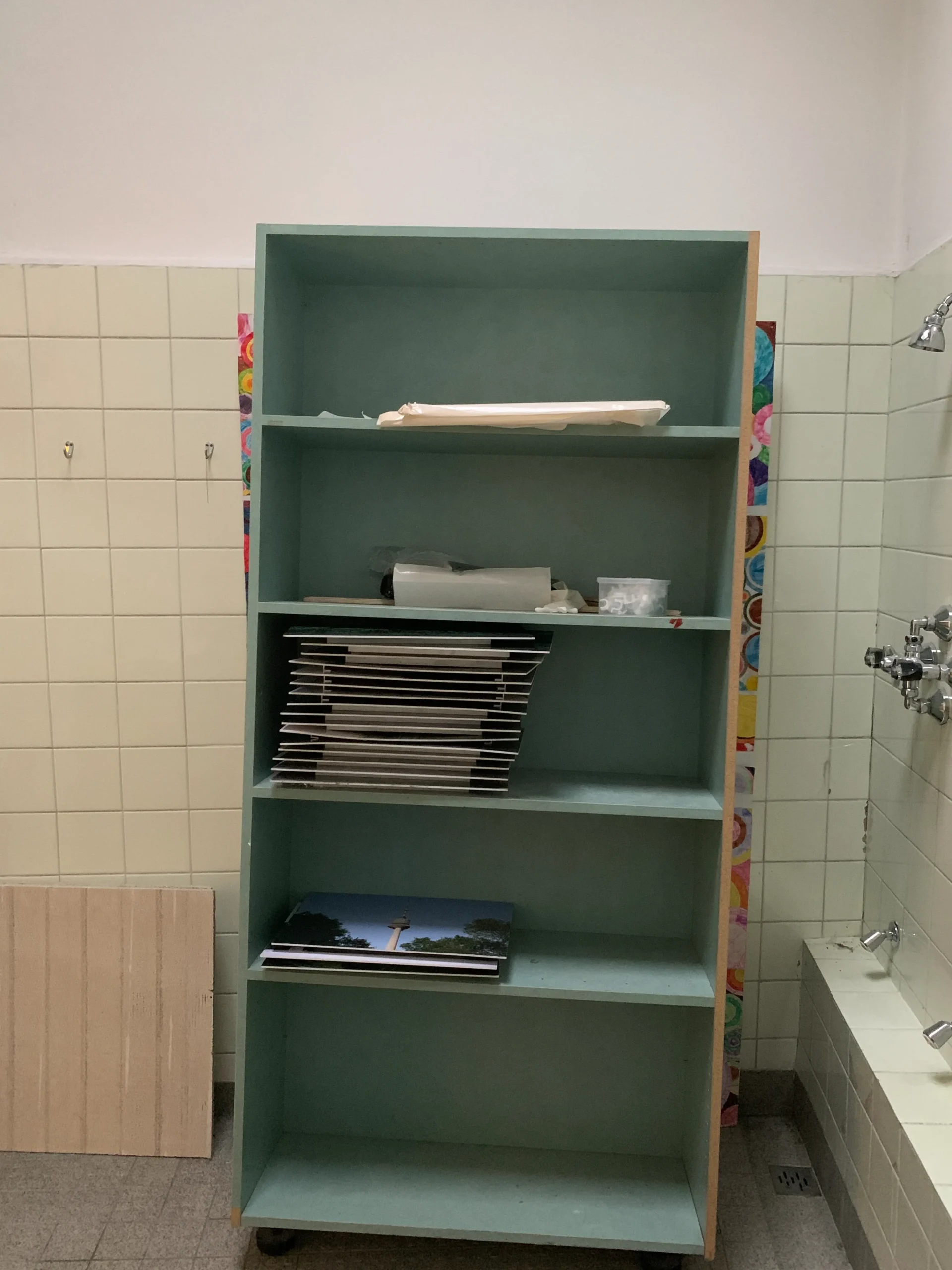 Before: mint-green shelving unit against the tiled walls of the old shower room